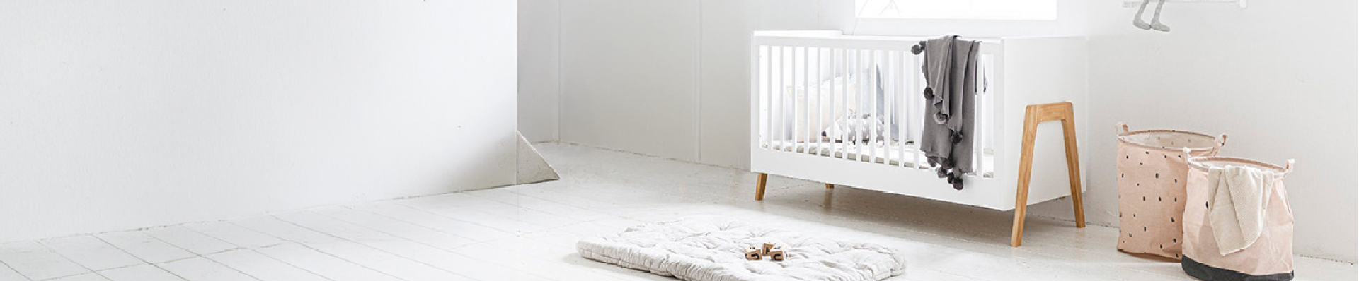 Babykamer met wit ledikant en speelkleed
